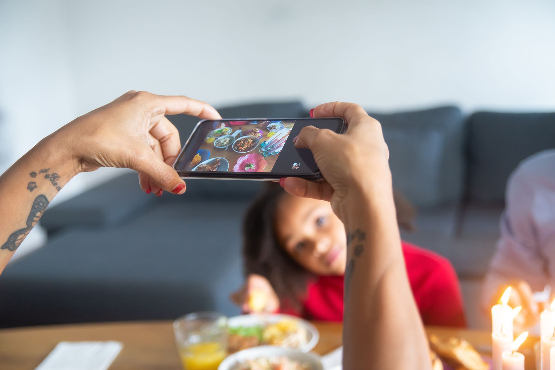 A smartphone displaying a glossy dessert photo beside a laptop showing a comments feed on a restaurant table