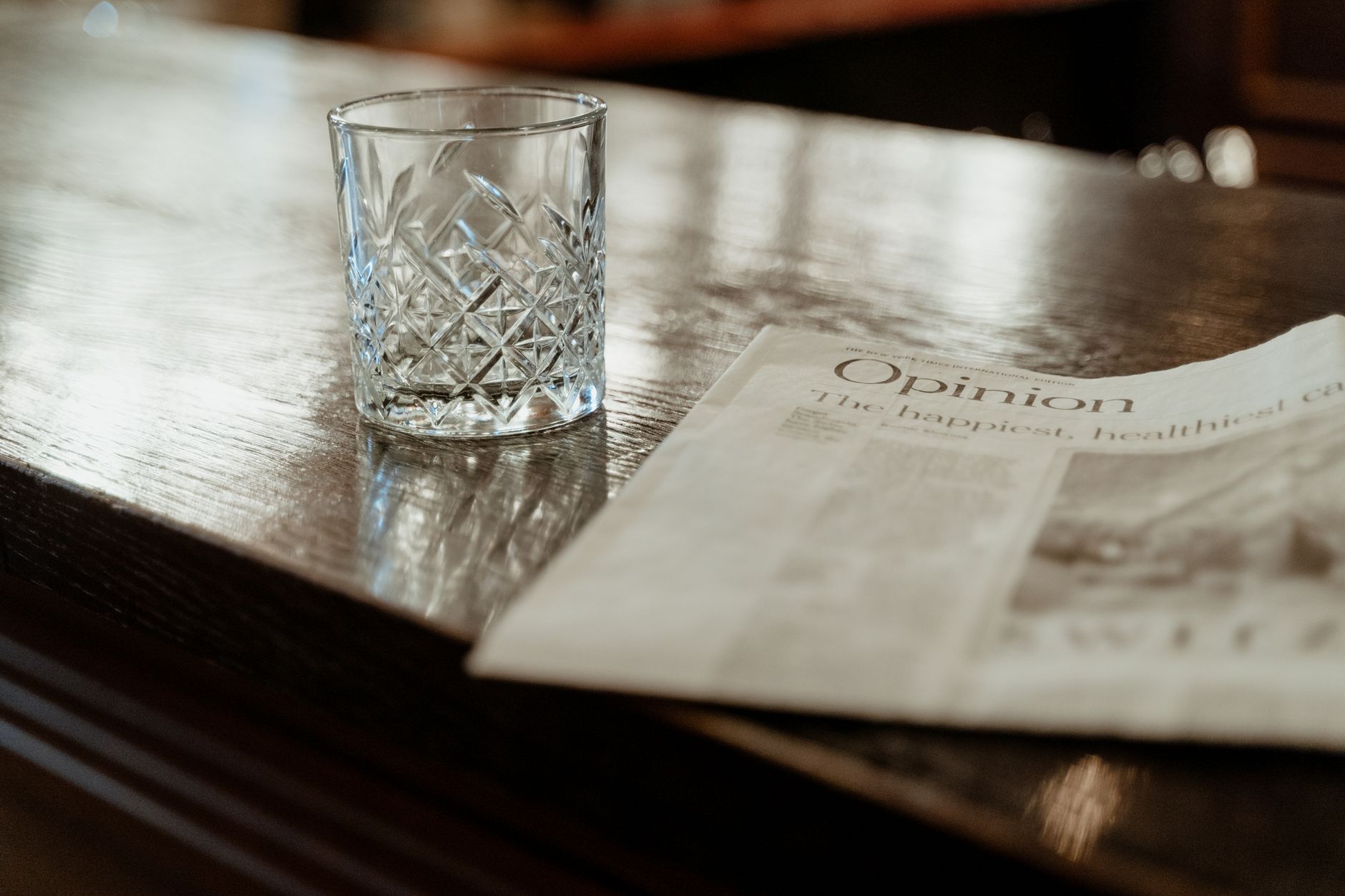 A newsroom opinion page spread open on a wooden desk next to a laptop showing a news homepage