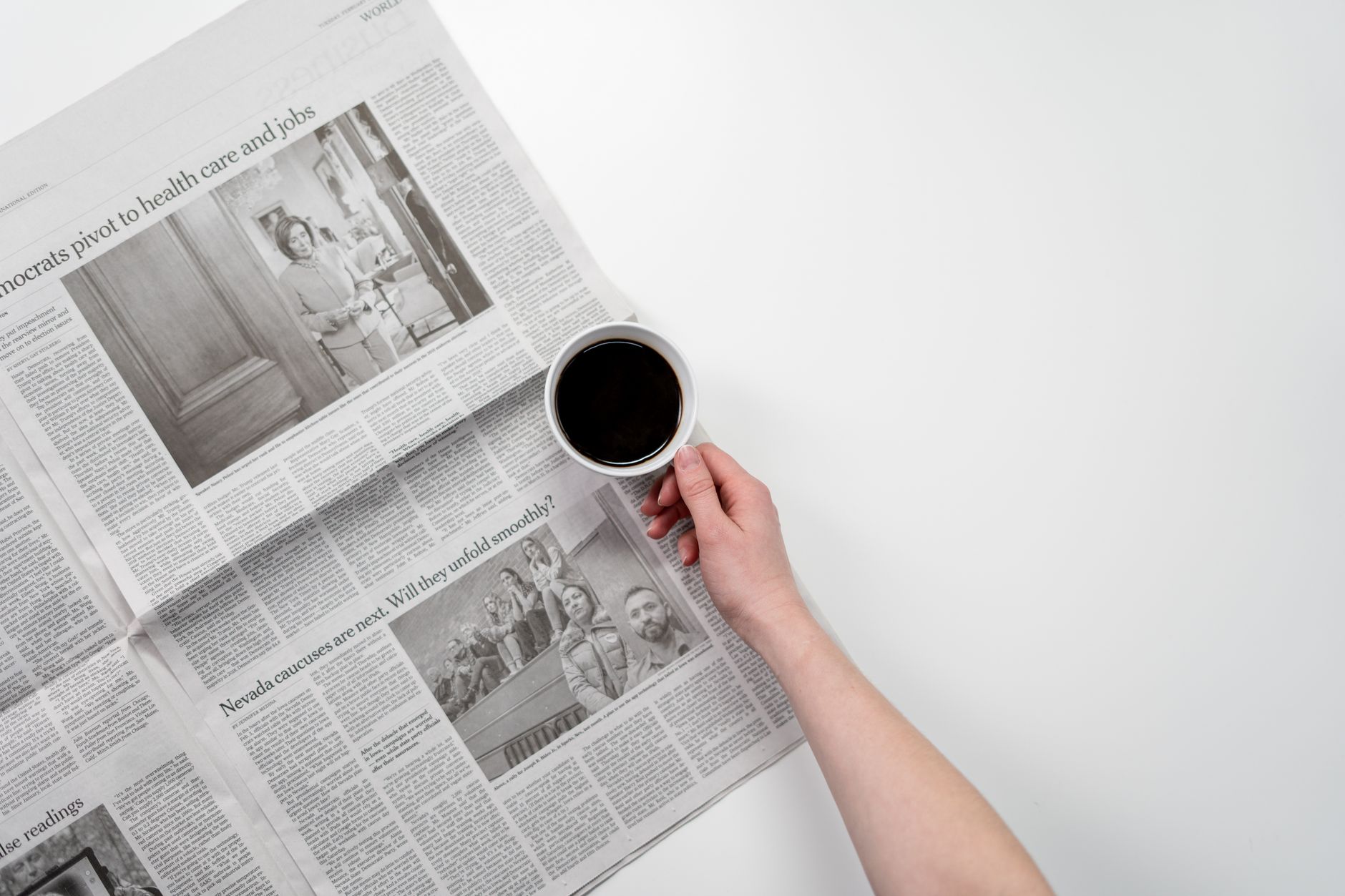 A folded local newspaper opinion page resting on a wooden desk with a coffee cup, morning light from a window